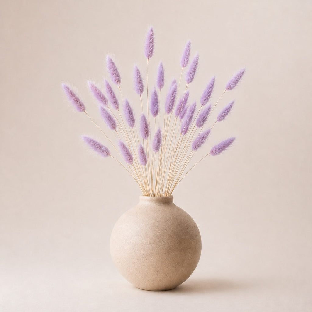 Beige vase with lilac dried bunny tails  (lagurus grass) on a beige background